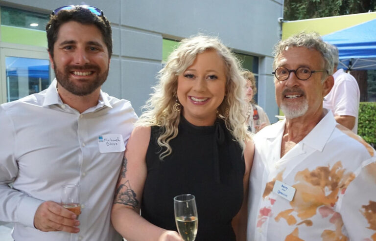 Three people standing in front of a building holding drinks.